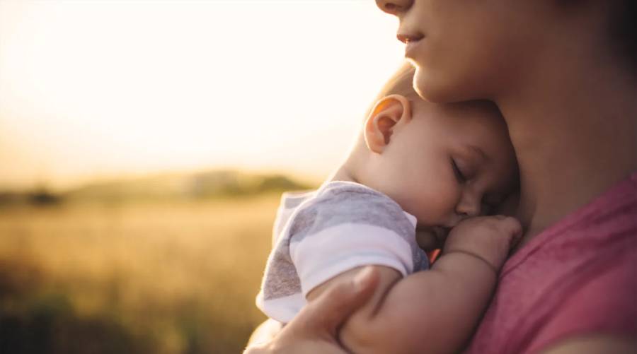 A loving mother cradles her baby in her arms, symbolizing care and protection against measles.