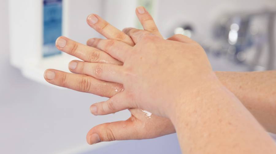 Person washing hands thoroughly under running water with soap