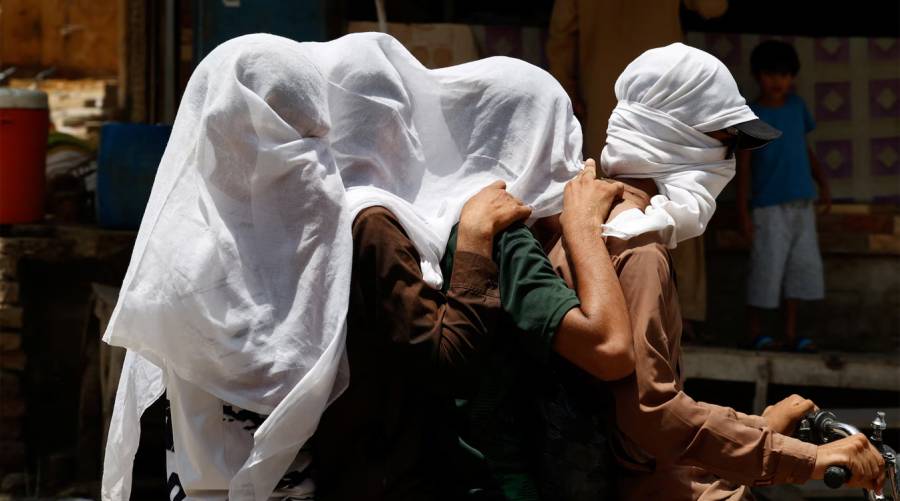 Men ride on a motorbike as they cover their heads with a wet cloth to cool off and to avoid sunlight, during a hot summer day, as the heatwave continues in Jacobabad, Sindh.