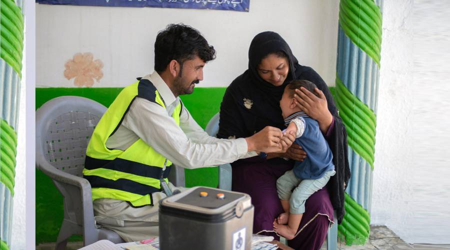 Vaccinator administering routine immunization to a child in Pakistan as part of WHO-supported health initiative
