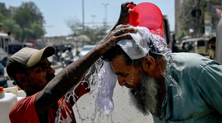 A volunteer pours water on a pedestrian's head to cool off during a hot summer day along a street in Karachi.