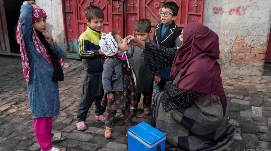 Polio health worker giving oral vaccine to child in Karachi during May 2025 amid refusal surge
