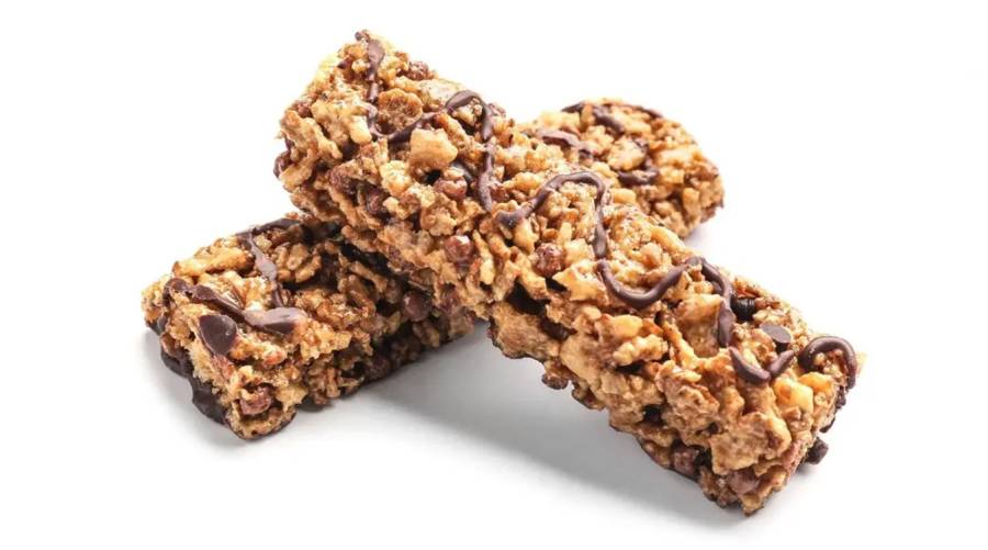 Close-up of protein bars on a cutting board with a scoop of protein powder in the background