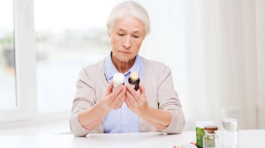 Older adult holding aspirin tablet and reading instructions following ASPREE-XT findings on bleeding risk and no heart benefit.