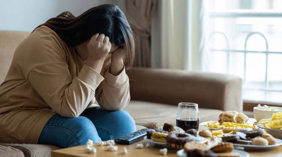 Person eating late-night snack under stress, symbolizing possible negative effects of circadian disruption on gut microbiome and digestion.