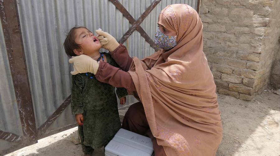 Pakistan polio vaccination worker administers oral polio vaccine to a child during an immunisation campaign