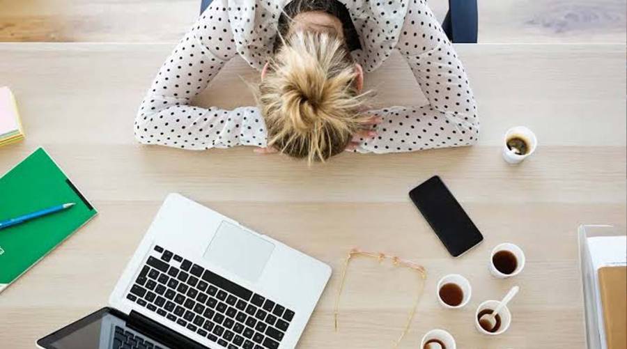 Adult experiencing daytime fatigue while sitting at a desk.